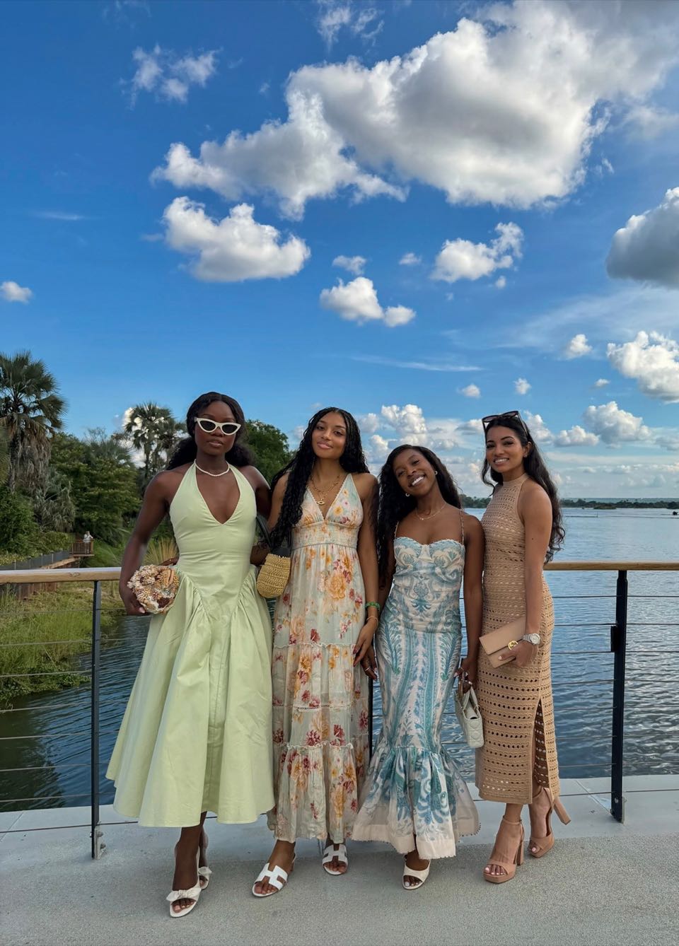 Four friends standing together on a riverside deck