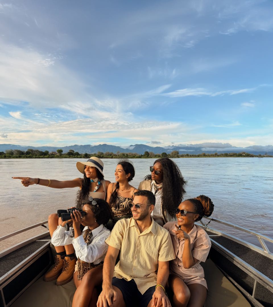 A group on a river boat, with one person pointing towards the bank