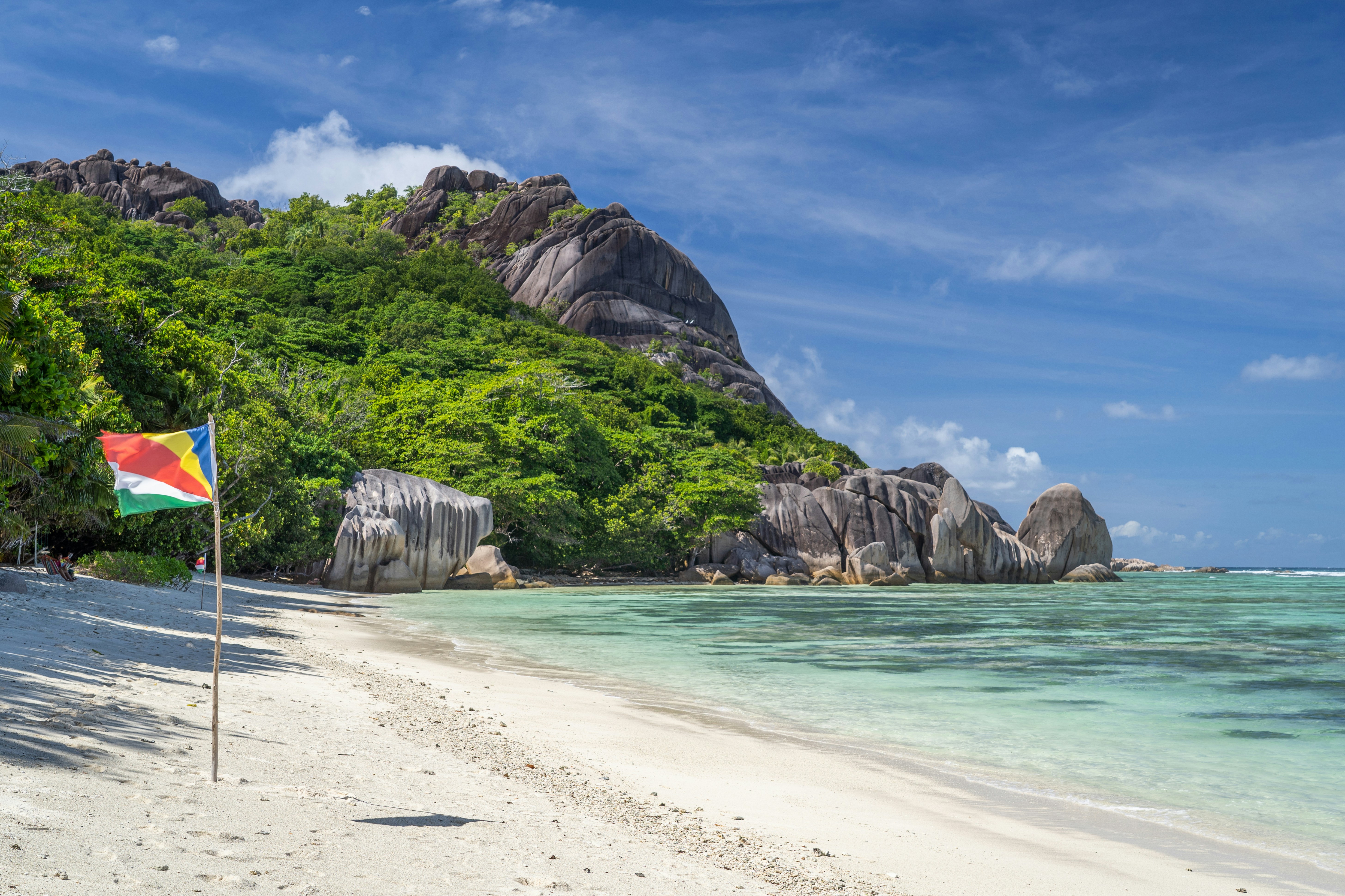 A white-sand beach with turquoise water and granite boulders